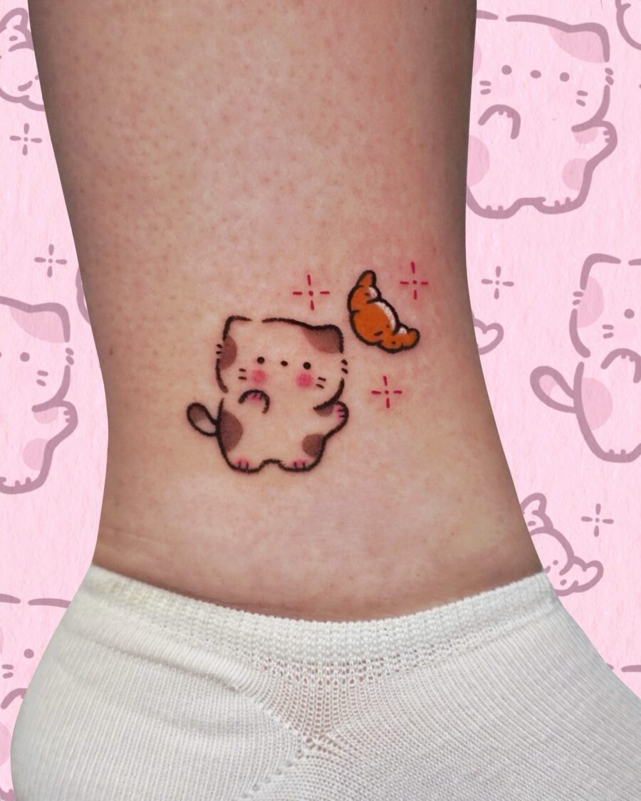 Adorable cat tattoo with a croissant charm Tattoo on skin