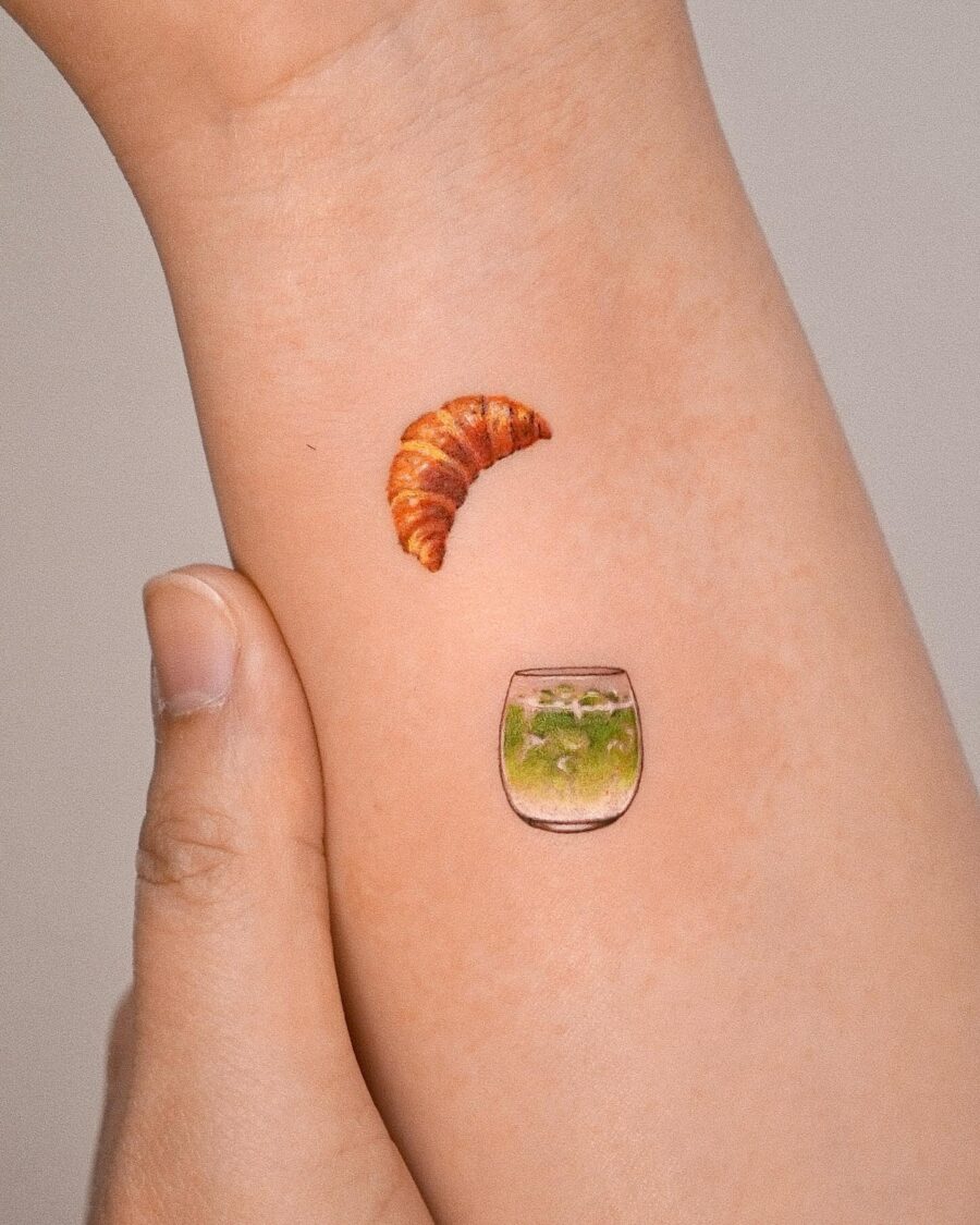 Charming croissant and vibrant drink tattoo. Tattoo on skin
