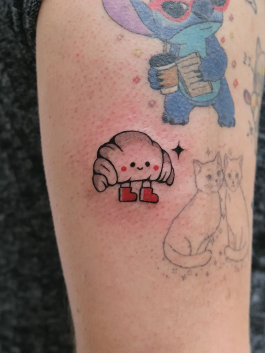Charming croissant tattoo with adorable features Tattoo on skin