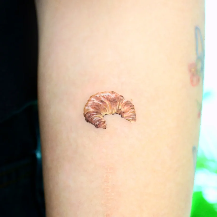 Charming realistic croissant tattoo on inner arm Tattoo on skin