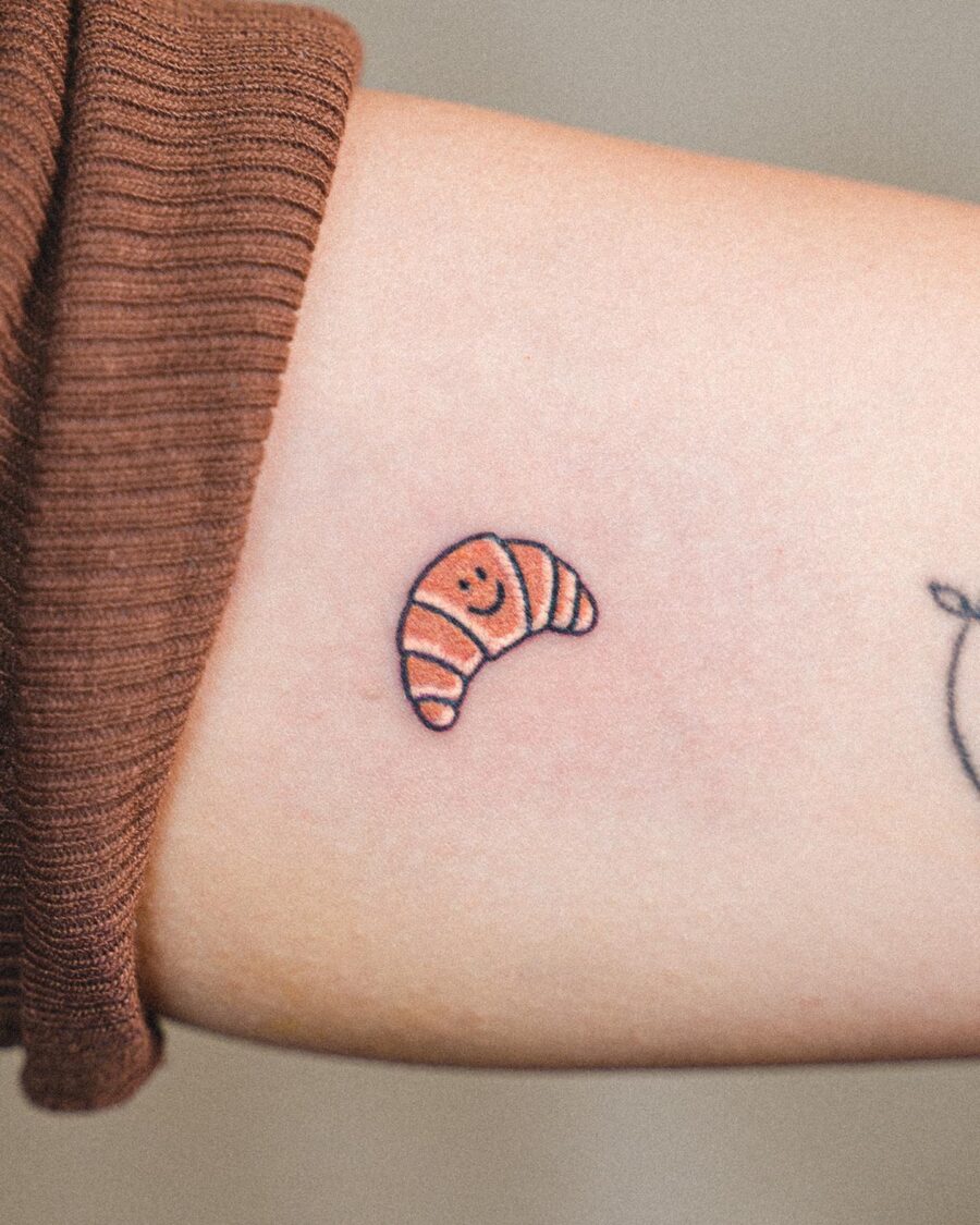 Charming small croissant tattoo with a smile Tattoo on skin