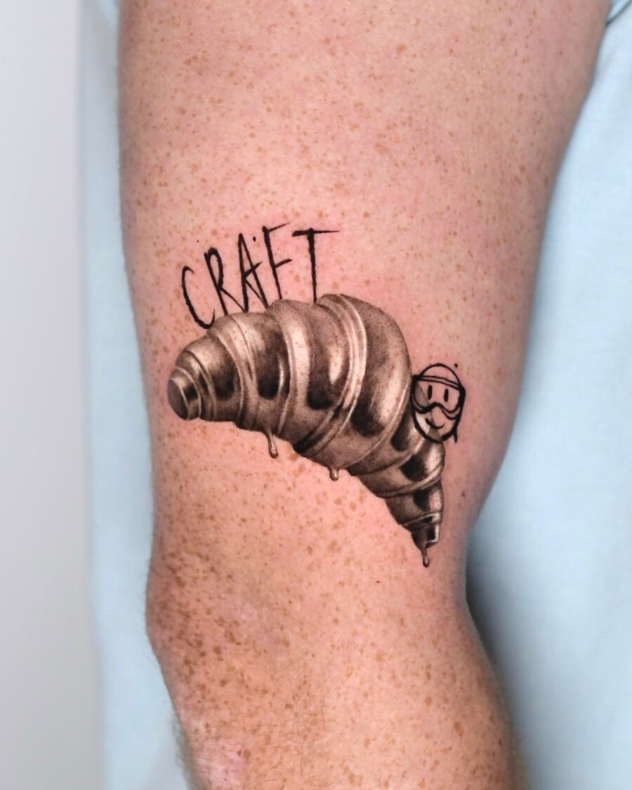 Playful Croissant Tattoo Featuring a Smiley Face Tattoo on skin