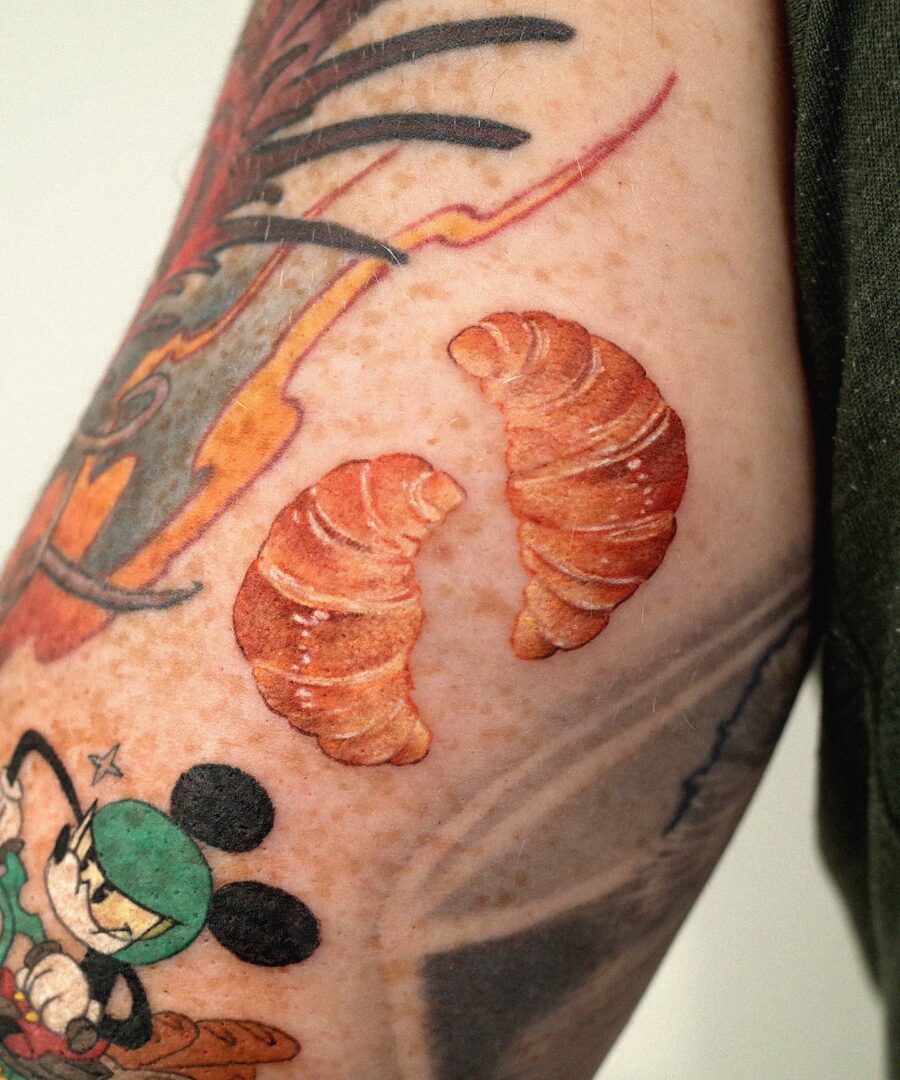 Whimsical croissant tattoos with cartoon influence Tattoo on skin