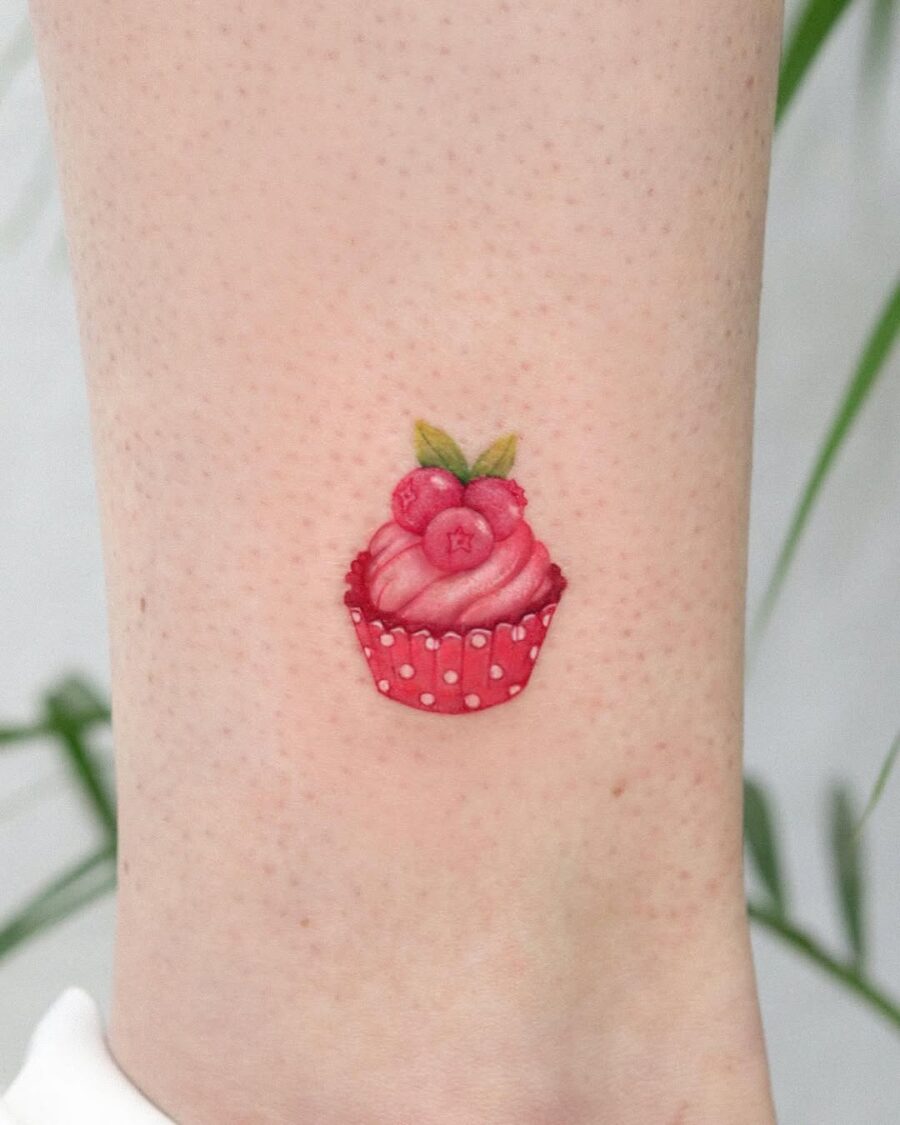 Charming pink cupcake tattoo with red accents Tattoo on skin