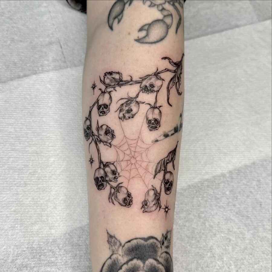 Intricate skulls entwined with delicate blooms Tattoo on skin