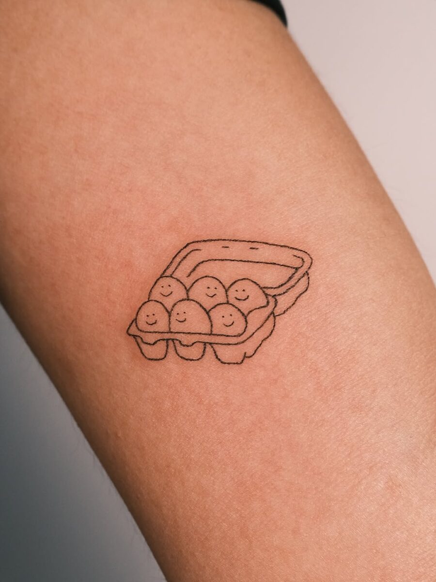 Adorable smiling eggs in a carton tattoo Tattoo on skin