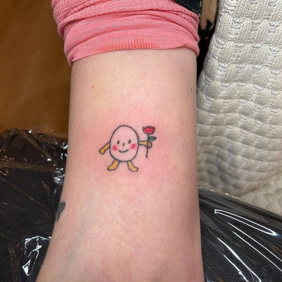 Charming egg character holding a flower tattoo Tattoo on skin