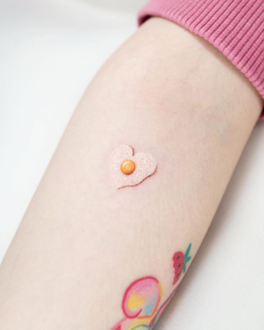Sweet heart-shaped egg tattoo with a pearl. Tattoo on skin
