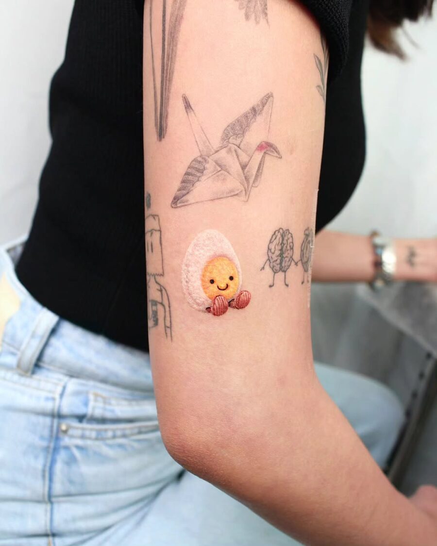 Whimsical cartoon egg tattoo in vibrant colors Tattoo on skin