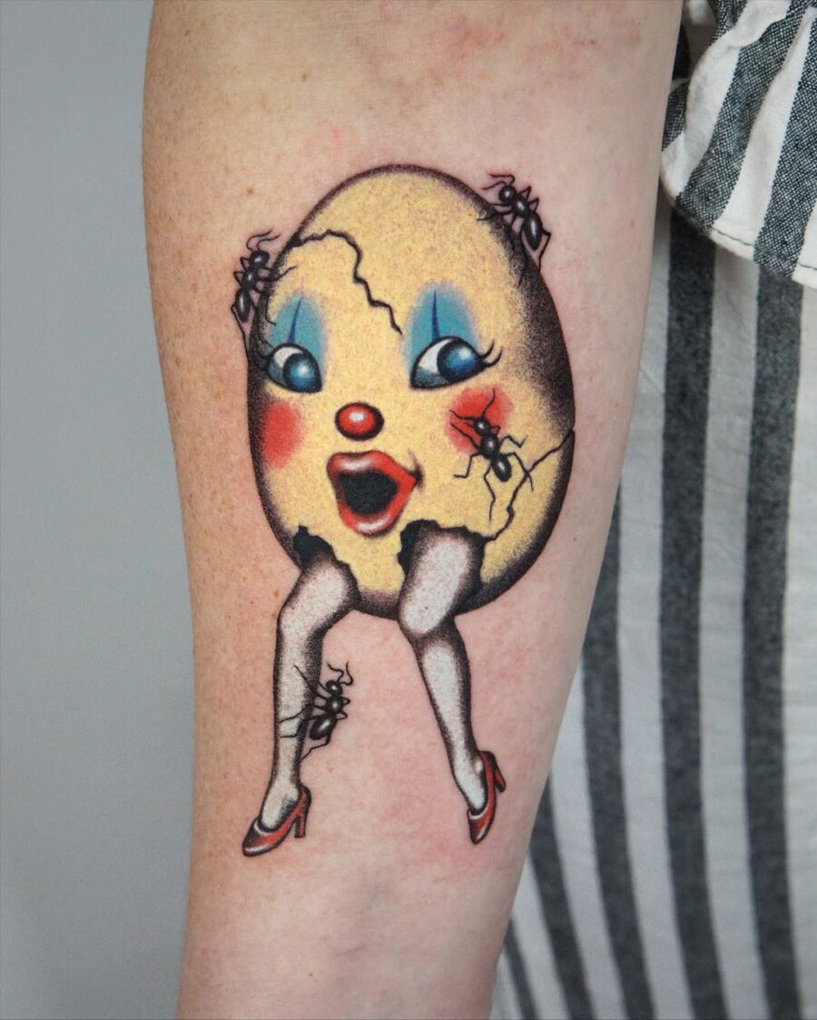 Whimsical egg tattoo featuring a playful character Tattoo on skin