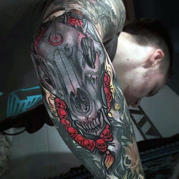 Decorated Canine Skull Tattoo with Chain of Human Skulls Elbow Tattoo Tattoo on skin