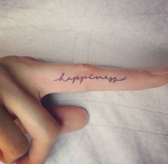 THE 'HAPPY' FINGER TATTOO ON A WOMAN Tattoo on skin