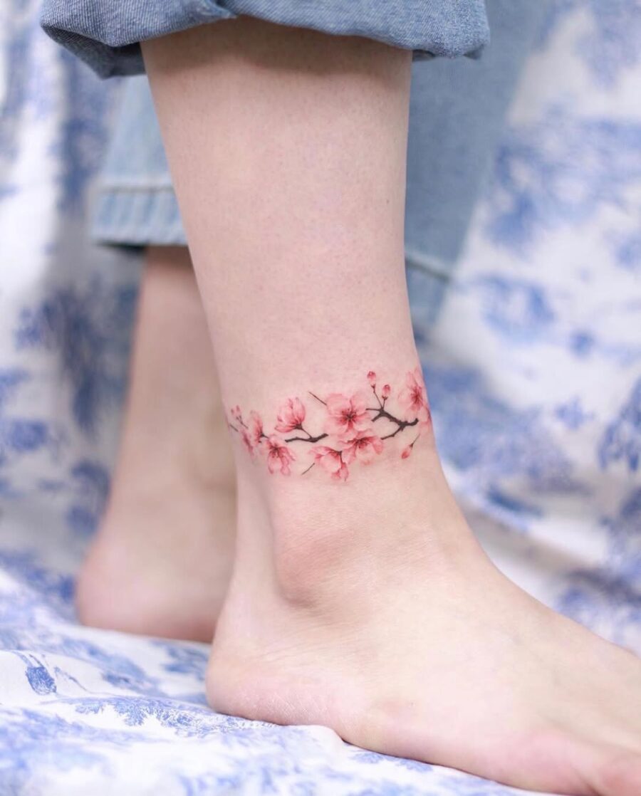 Elegant pink blossoms wrapping around the ankle Tattoo on skin