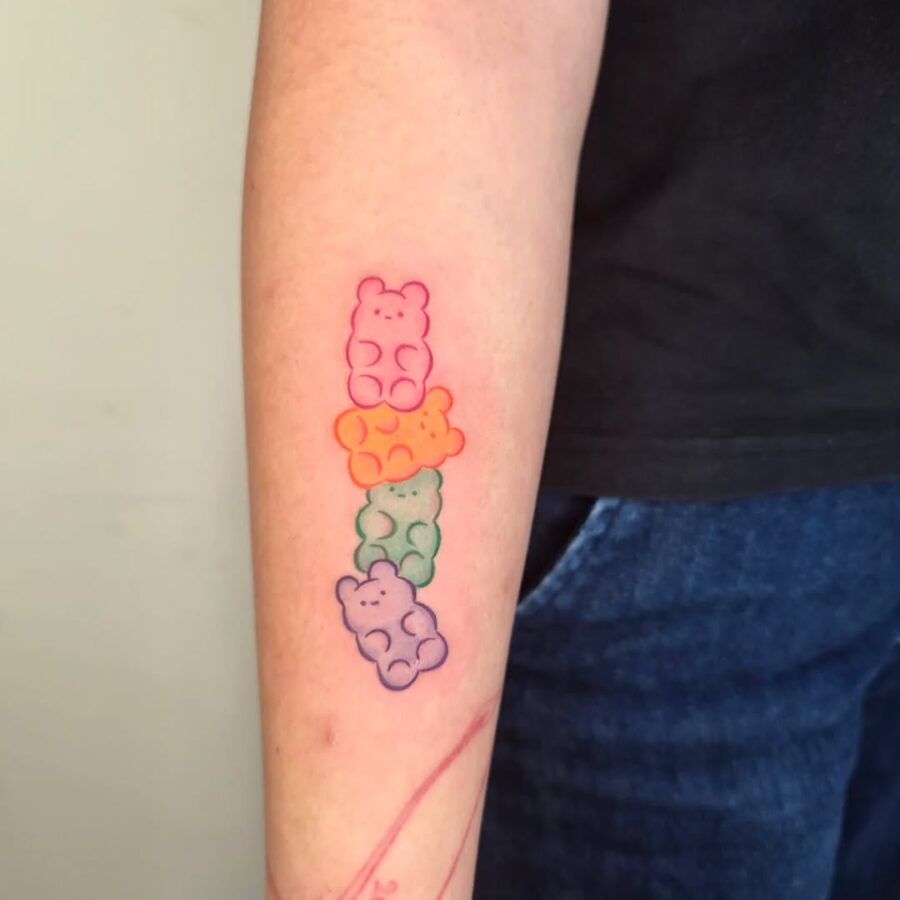Colorful gummy bears adorned on forearm. Tattoo on skin