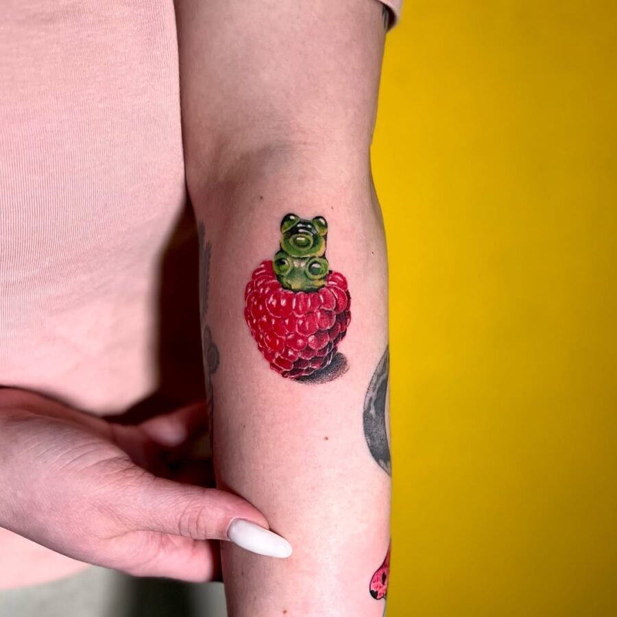 Whimsical gummy bear atop a berry tattoo Tattoo on skin