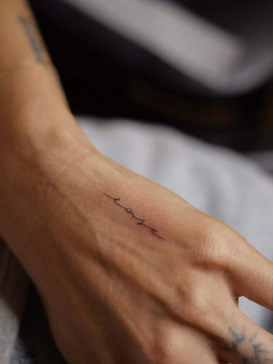 Delicate Handwriting Tattoo of the Word 'Ease' Tattoo on skin