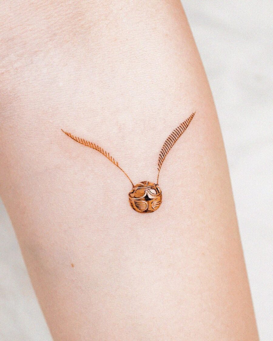 Elegant golden snitch tattoo design on skin Tattoo on skin