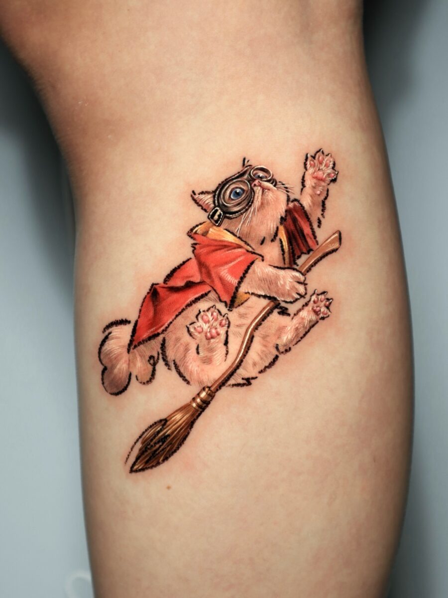 Whimsical feline on a flying broomstick tattoo Tattoo on skin