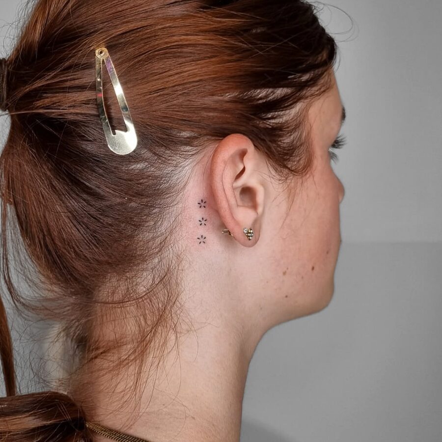 Delicate floral tattoo discreetly placed behind ear Tattoo on skin