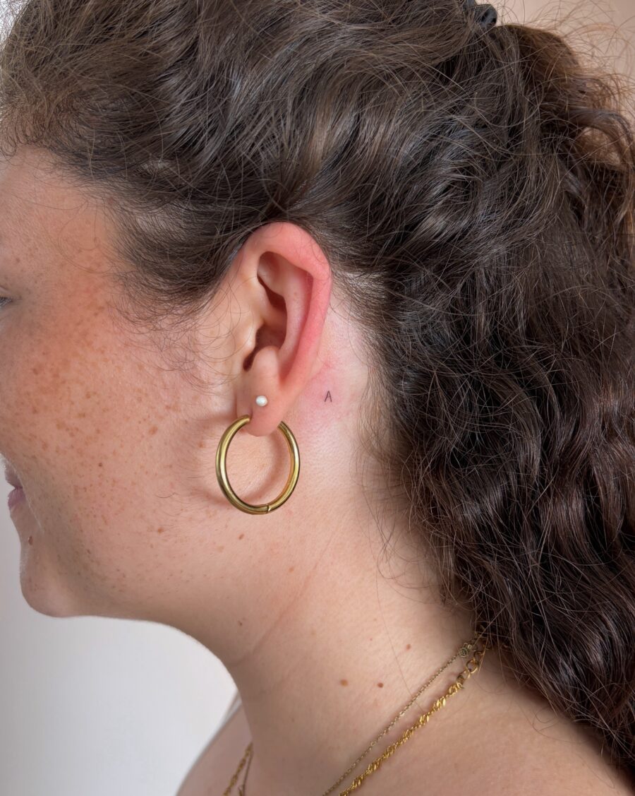 Subtle ear tattoo peeking from behind hair Tattoo on skin