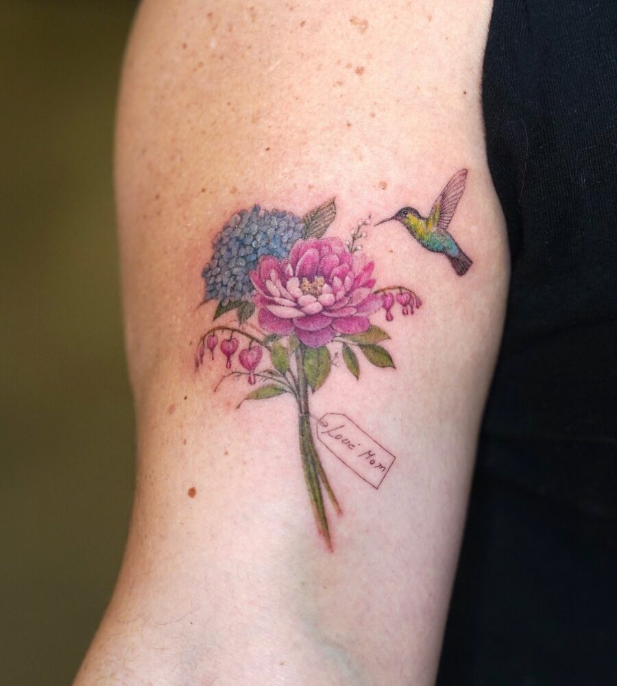 A vibrant tribute with flowers and a hummingbird Tattoo on skin