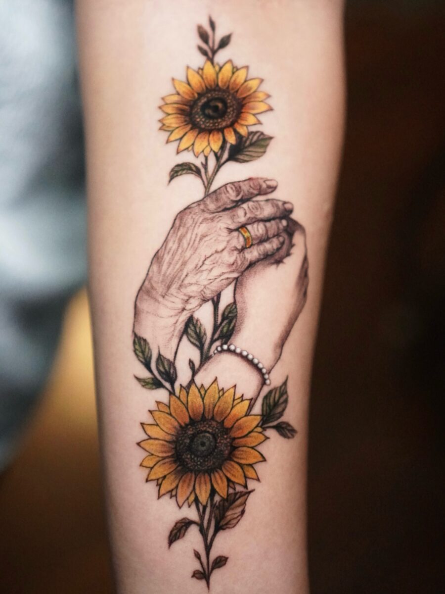 Symbolic hands and sunflowers in memory Tattoo on skin