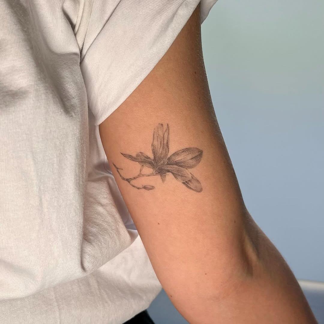 Elegant magnolia tattoo on a relaxed arm. Tattoo on skin
