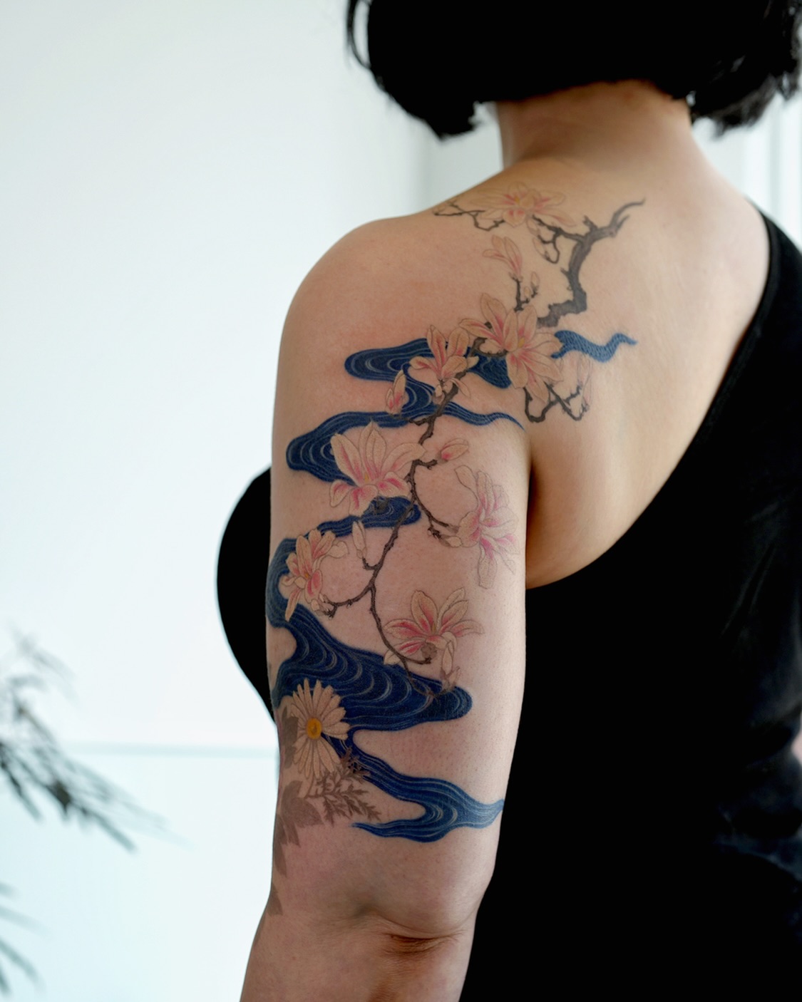 Elegant magnolia tattoo with flowing waves Tattoo on skin