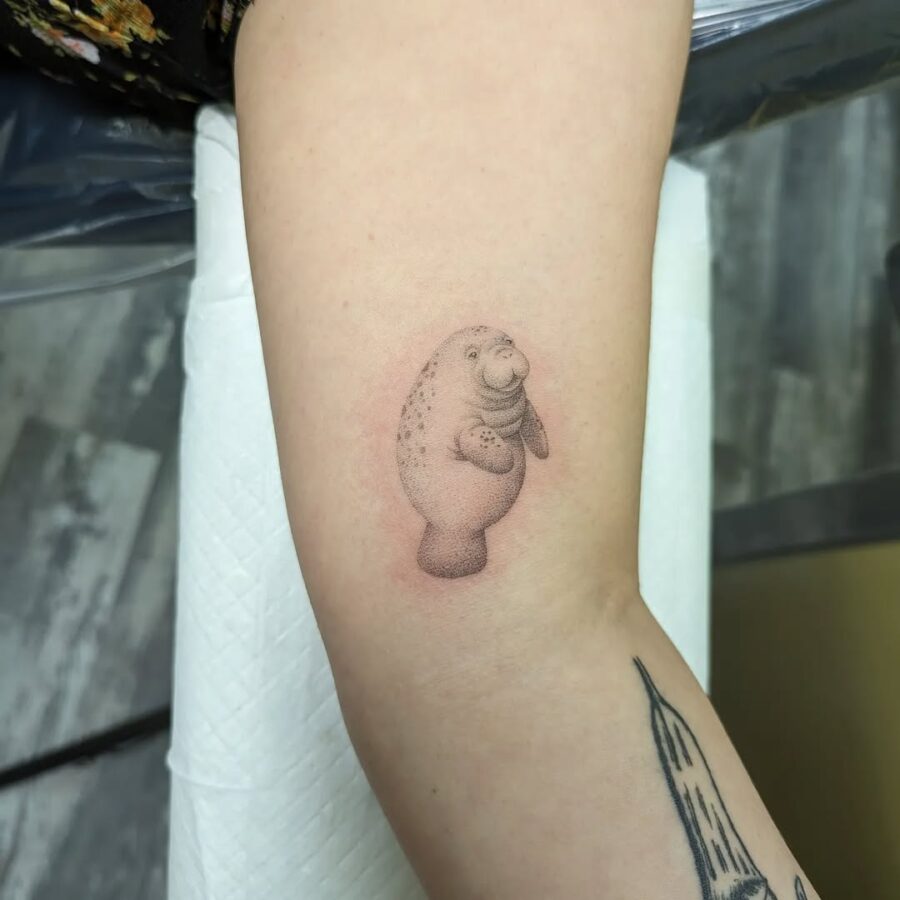 Charming manatee tattoo brings playful vibes. Tattoo on skin