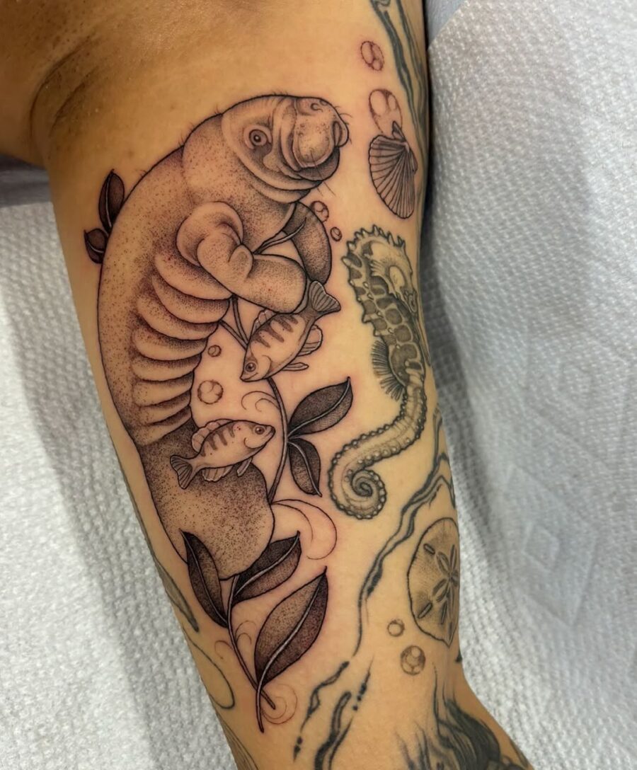 Charming manatee tattoo surrounded by aquatic life Tattoo on skin