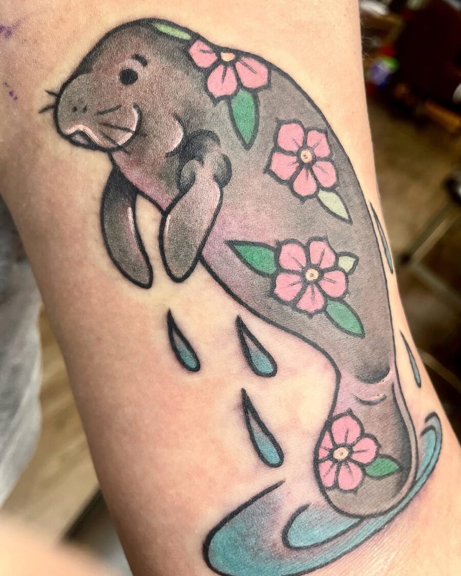 Charming manatee tattoo with floral accents Tattoo on skin