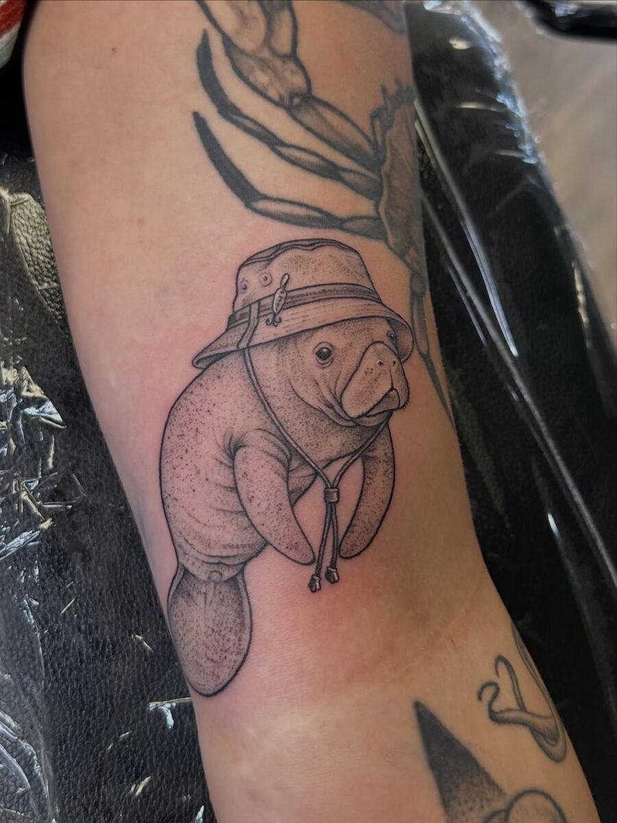 Playful Manatee Tattoo in a Stylish Hat Tattoo on skin