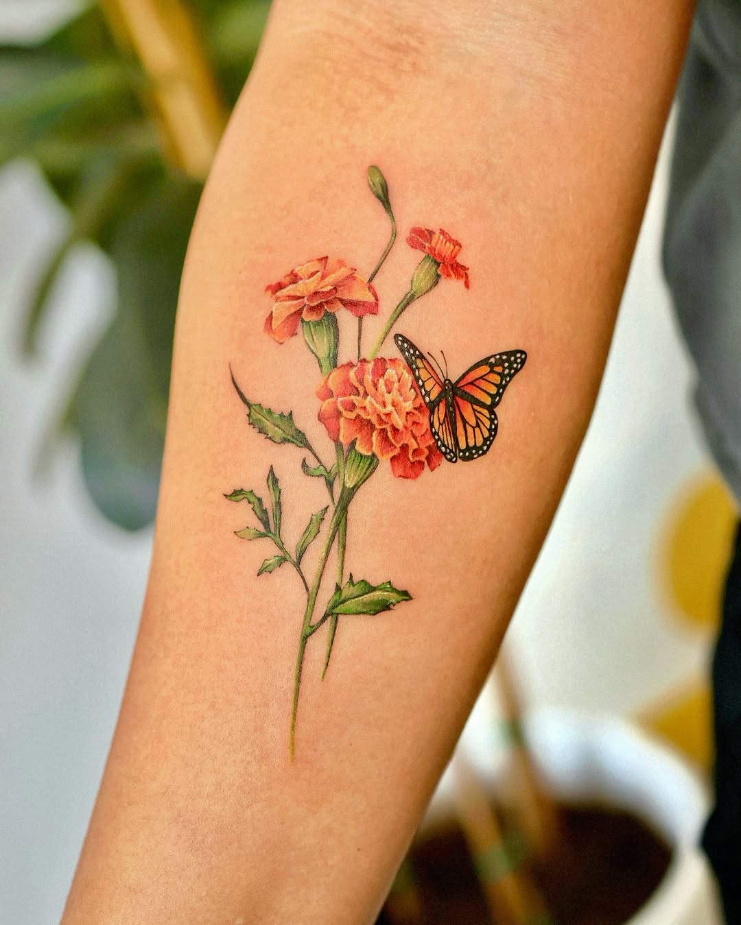Colorful marigold tattoo featuring a butterfly Tattoo on skin