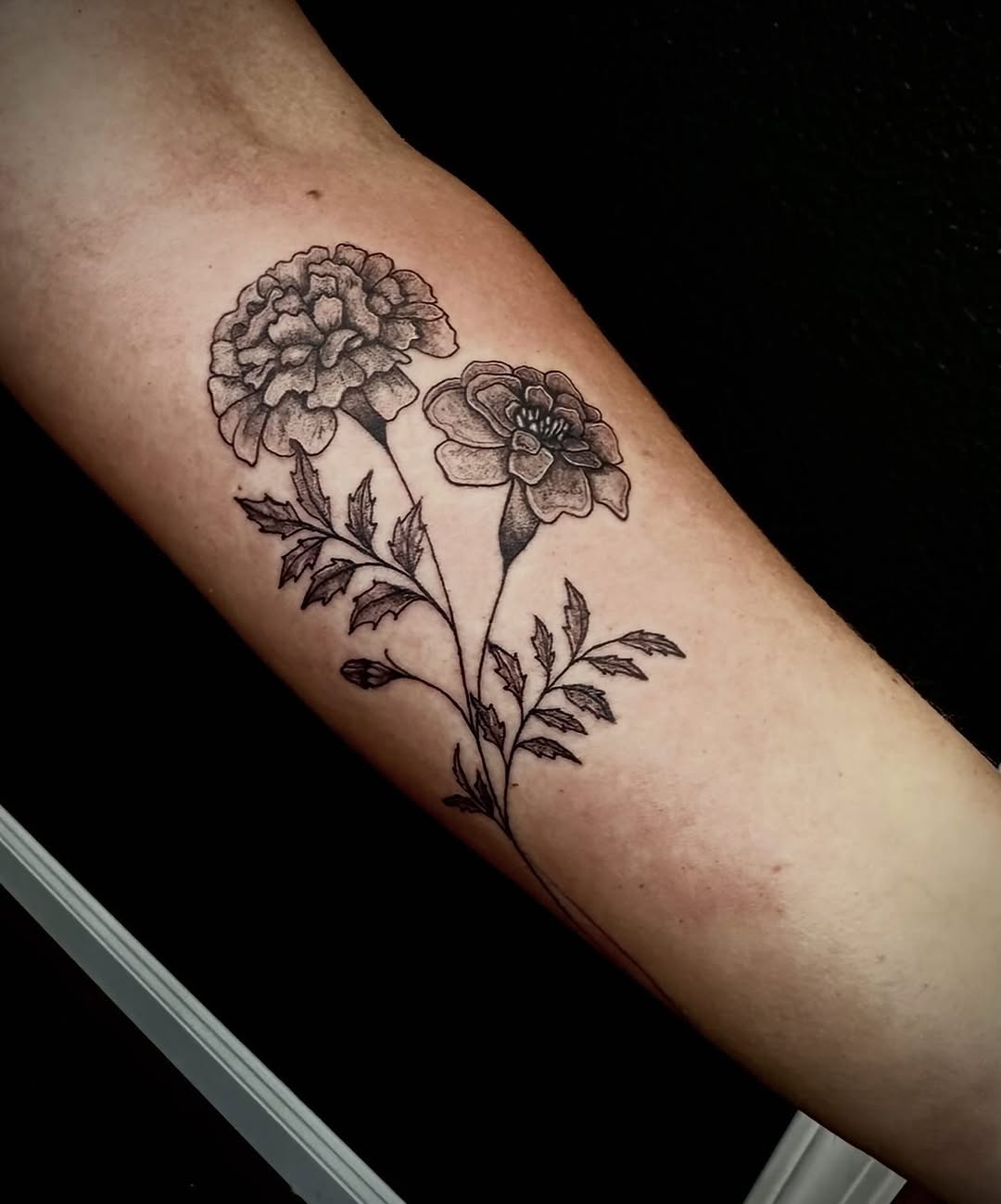 Elegant marigold tattoo design in black ink Tattoo on skin
