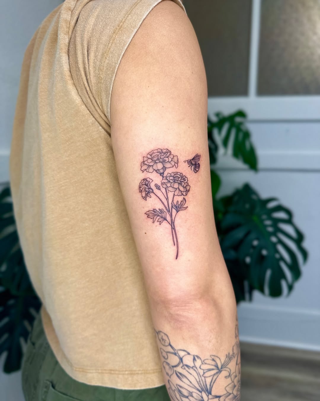 Elegant marigold tattoo with delicate bee Tattoo on skin