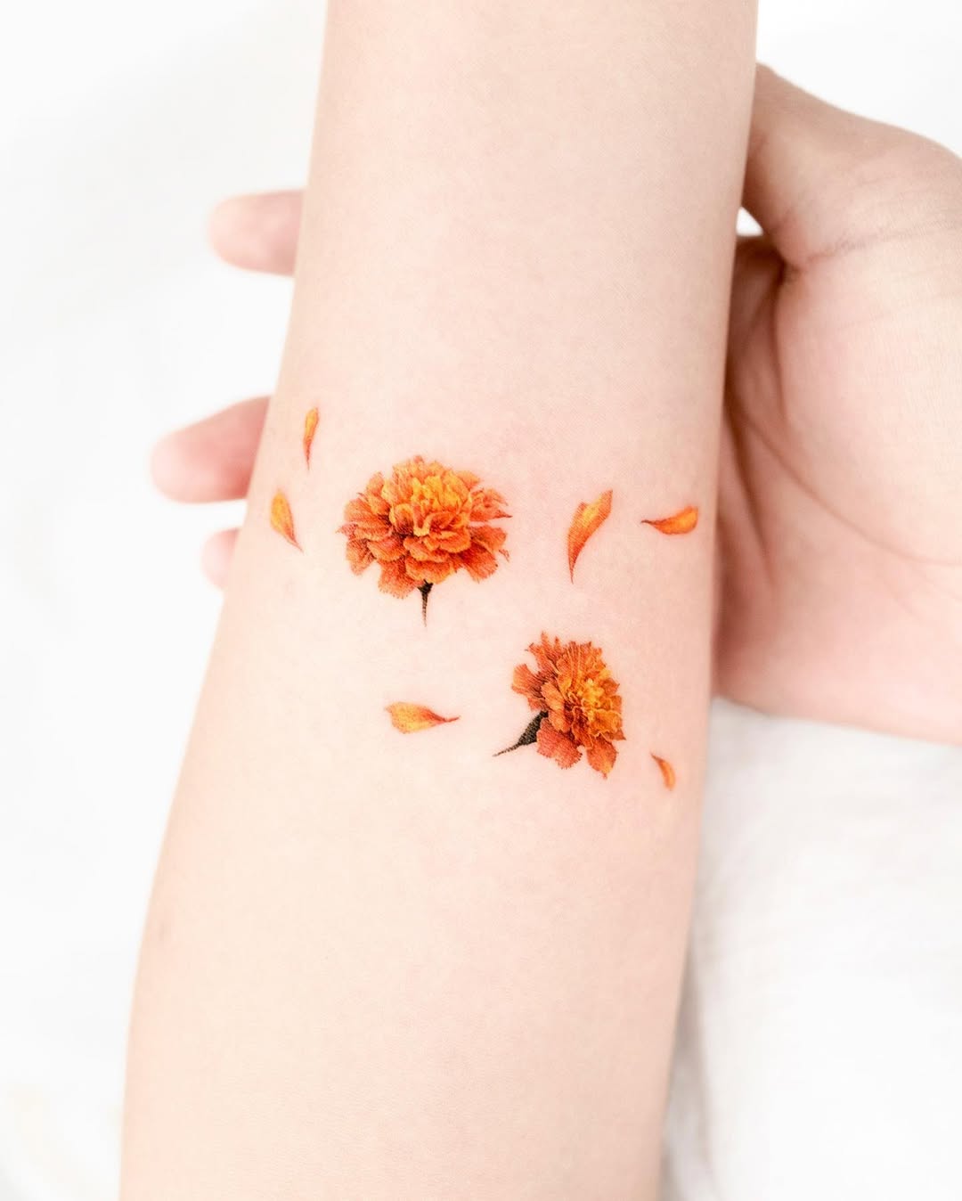 Vibrant marigold tattoo with delicate petals. Tattoo on skin