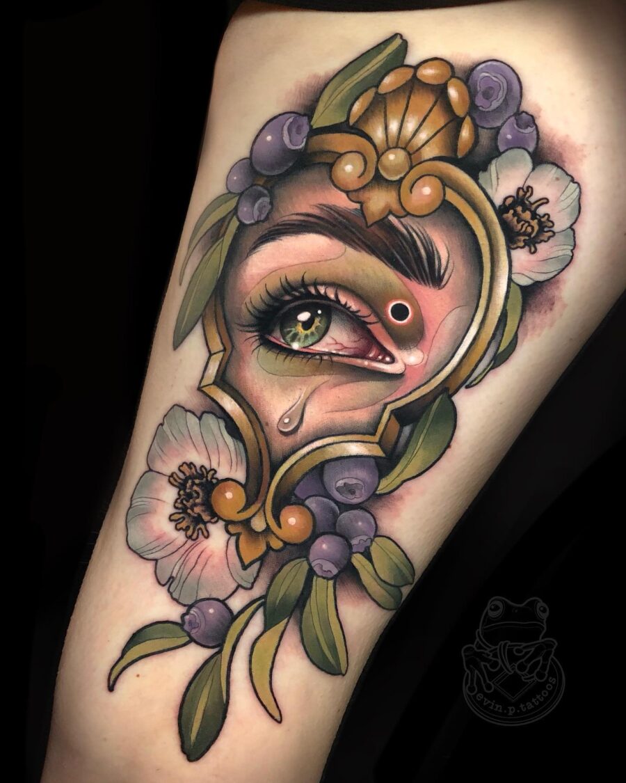 Intricate eye surrounded by floral elements. Tattoo on skin