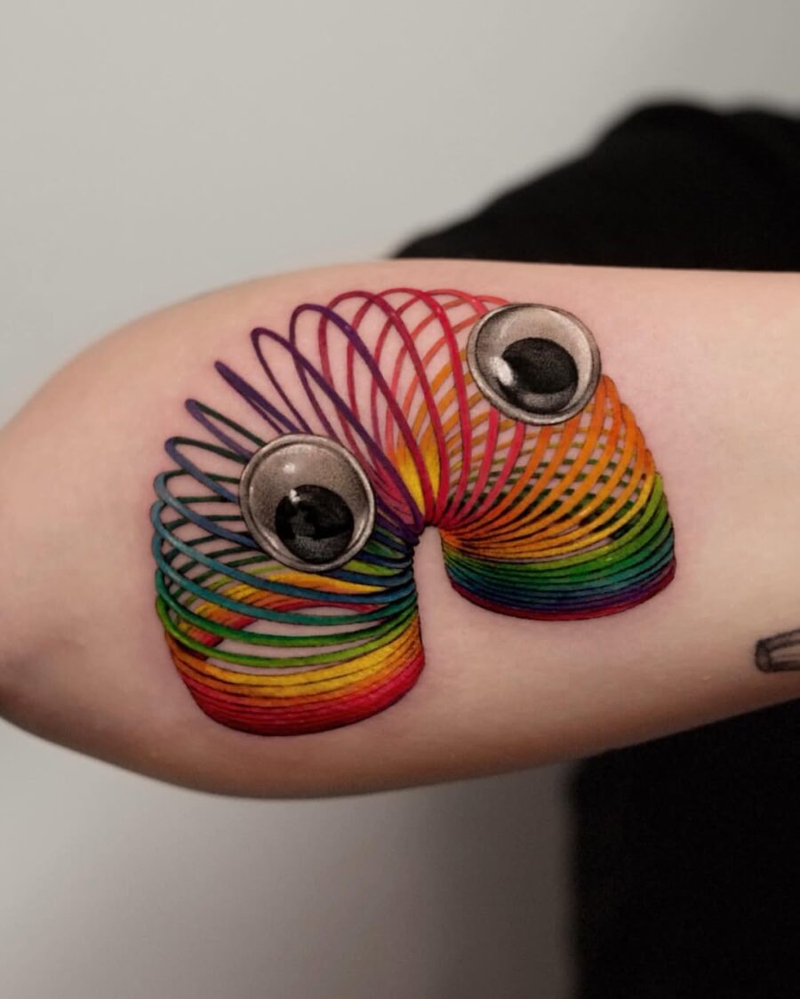 Vibrant slinky tattoo with whimsical googly eyes Tattoo on skin