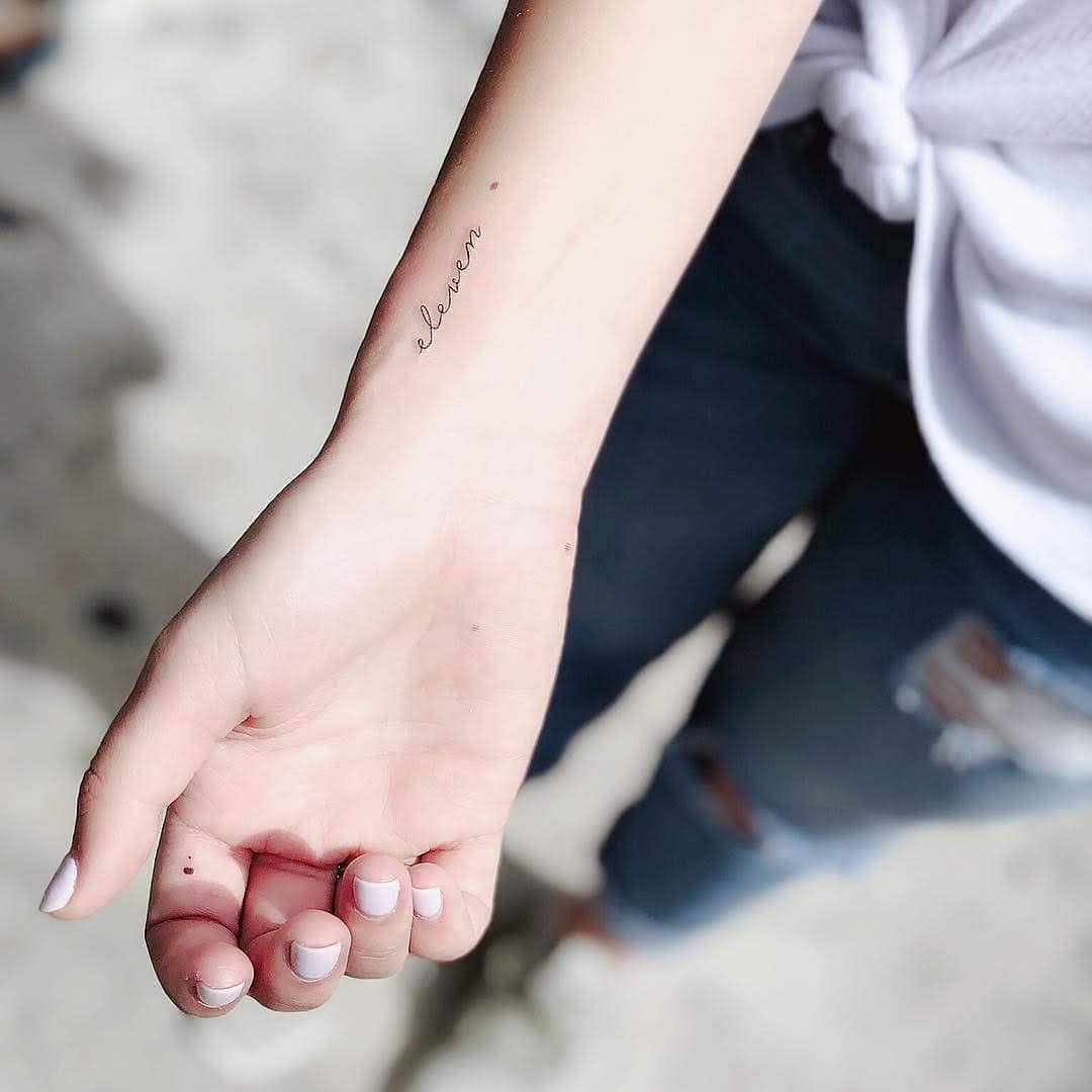 Minimalist tattoo featuring the word 'eleven' Tattoo on skin