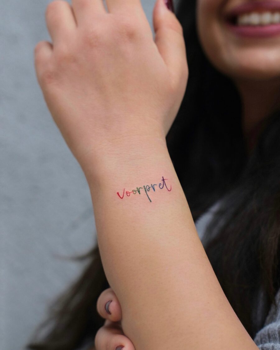 Colorful one-word tattoo on wrist Tattoo on skin