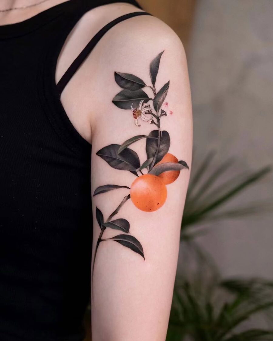 A vibrant orange tattoo surrounded by leaves Tattoo on skin