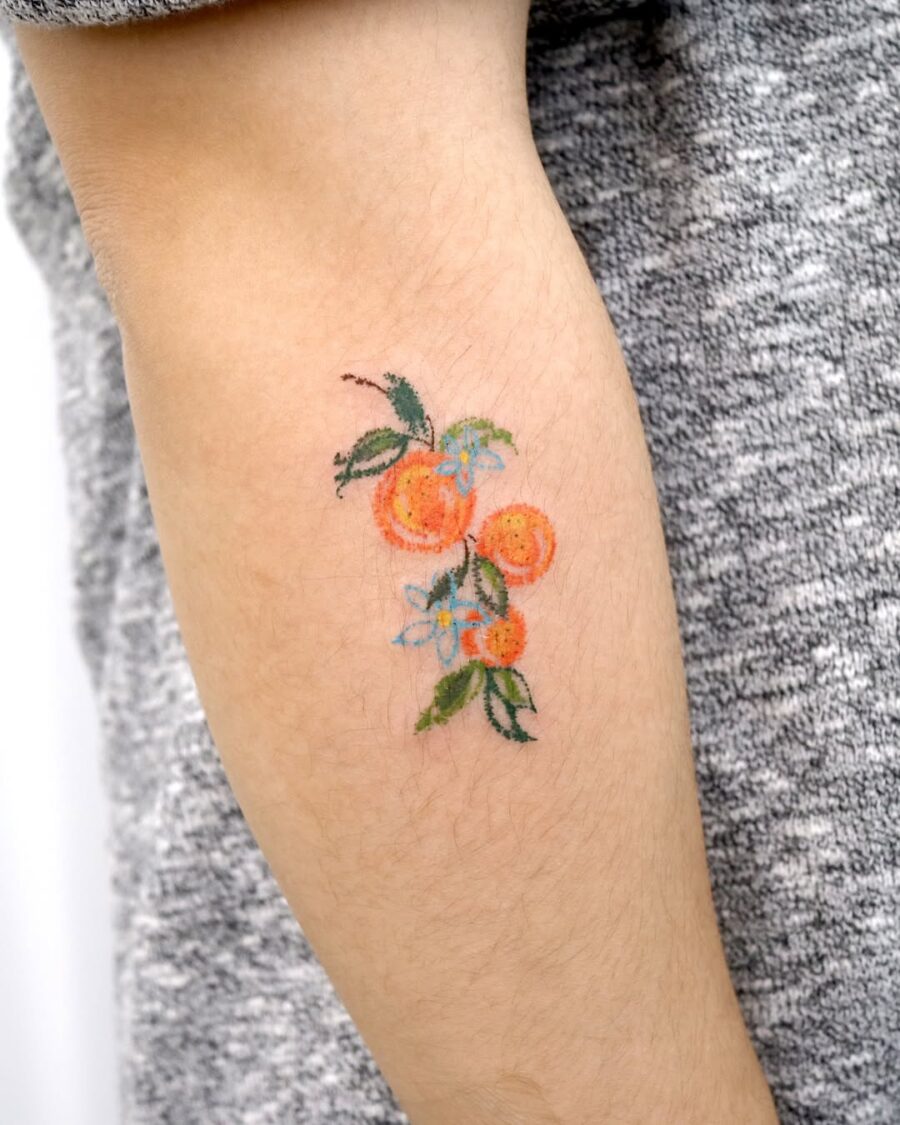 Vibrant orange fruit tattoo with floral accents Tattoo on skin