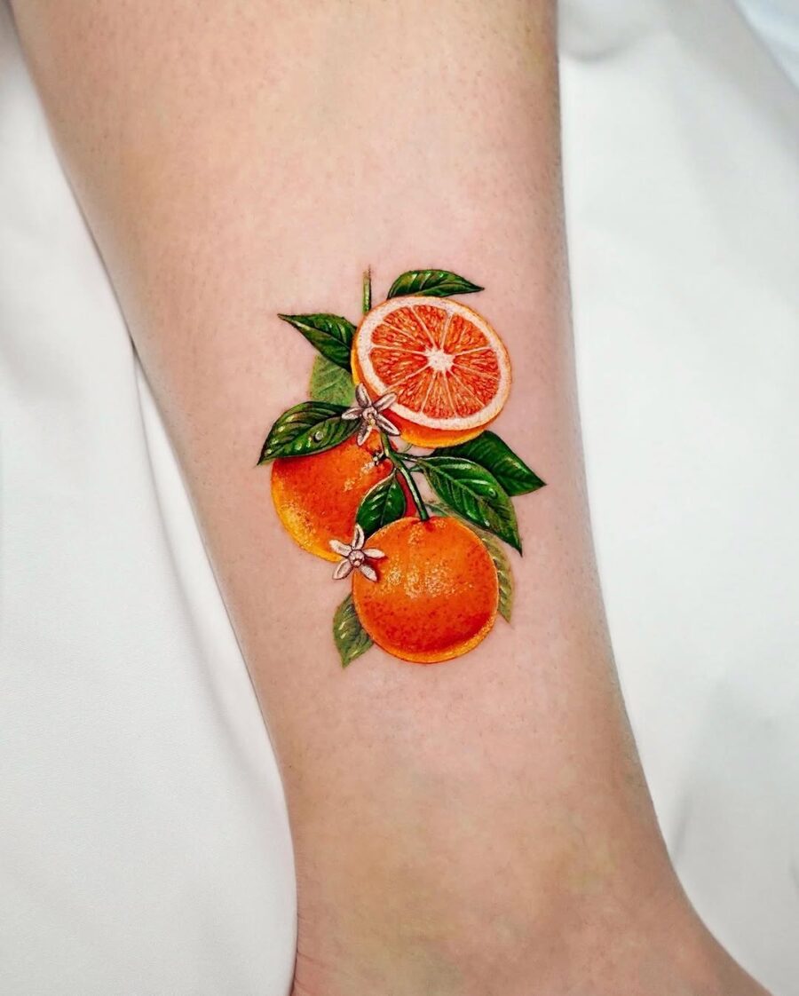 Vibrant Orange Fruit Tattoo with Leaves Tattoo on skin