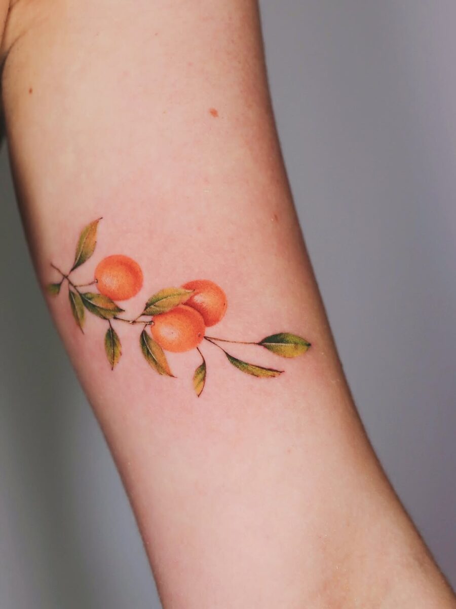 Vibrant orange tattoo with delicate leaves Tattoo on skin