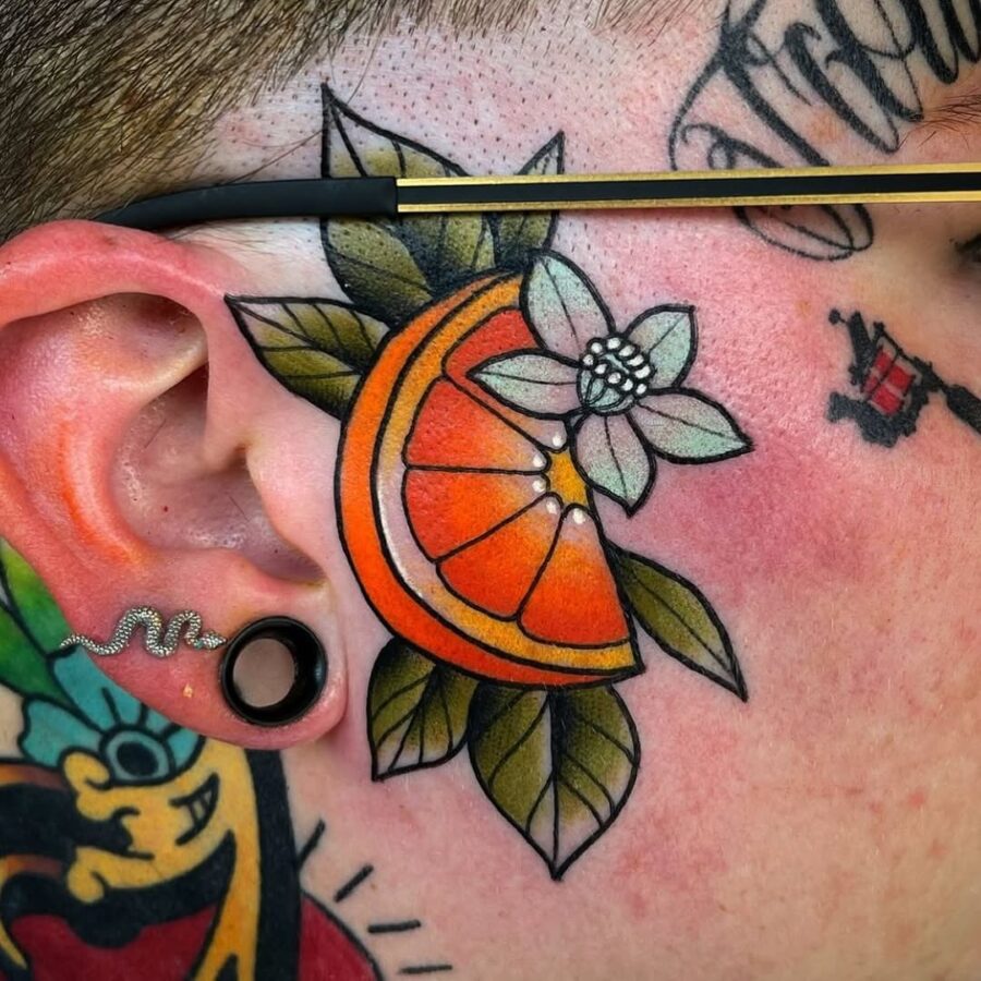 Vibrant orange tattoo with floral accents on skin. Tattoo on skin