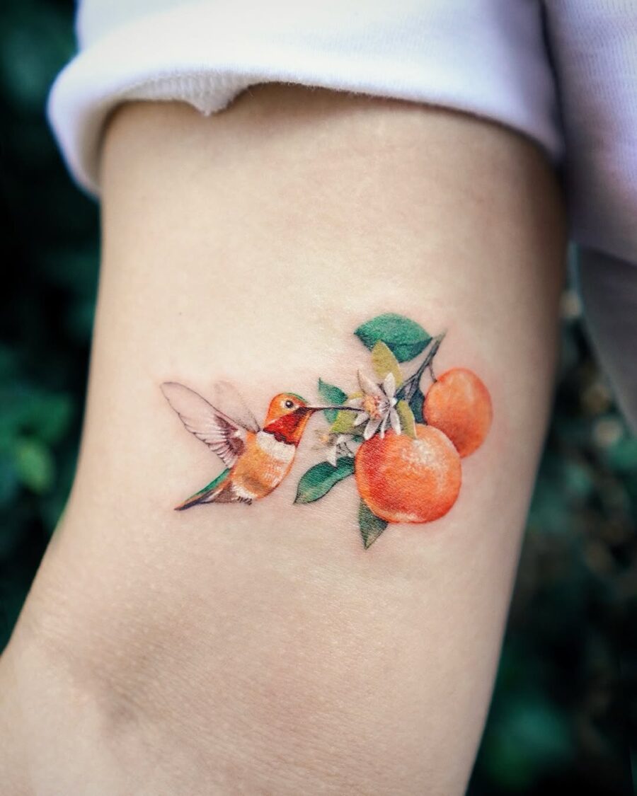 Vibrant tattoo featuring a hummingbird and oranges Tattoo on skin