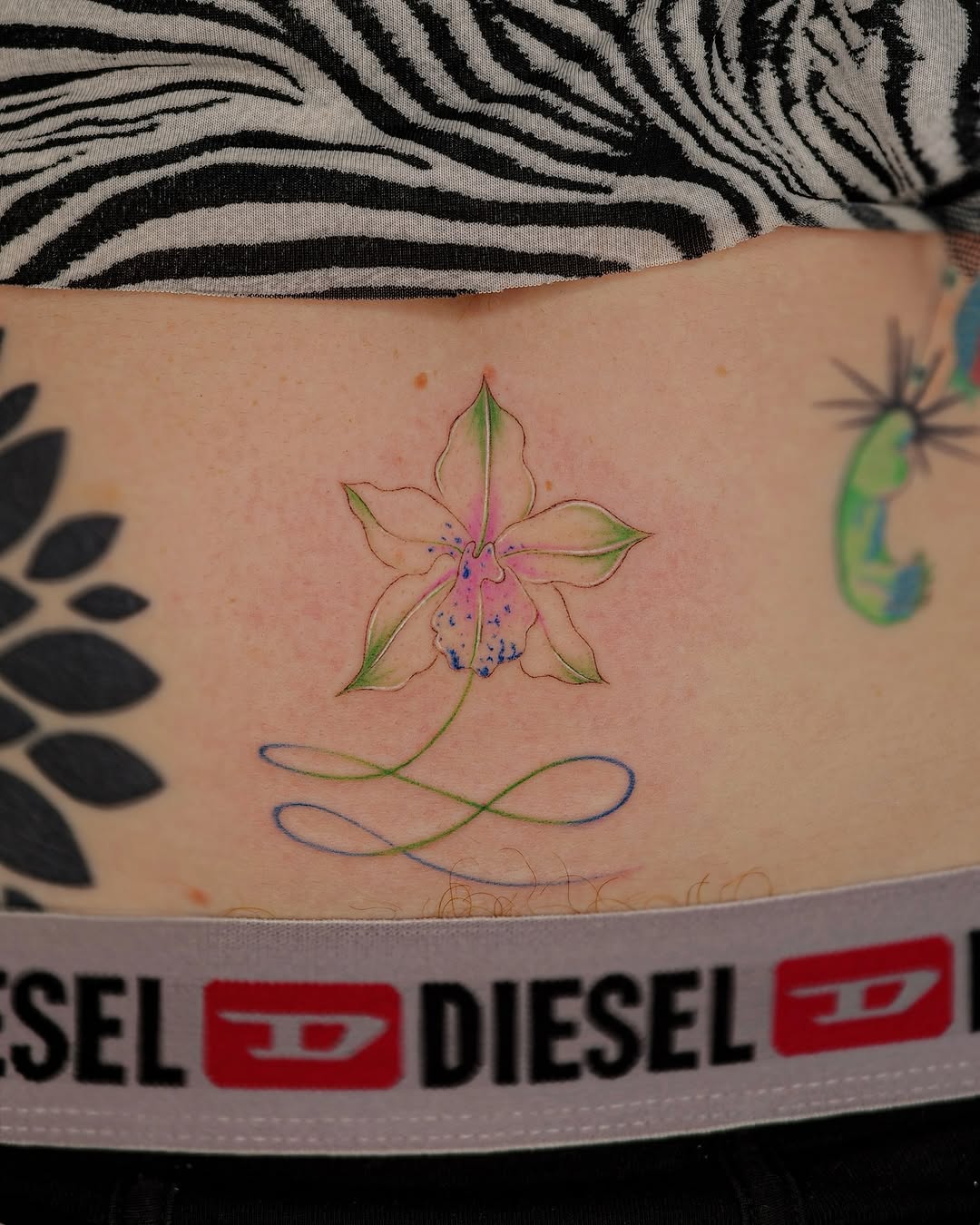 Elegant orchid tattoo with delicate lines. Tattoo on skin