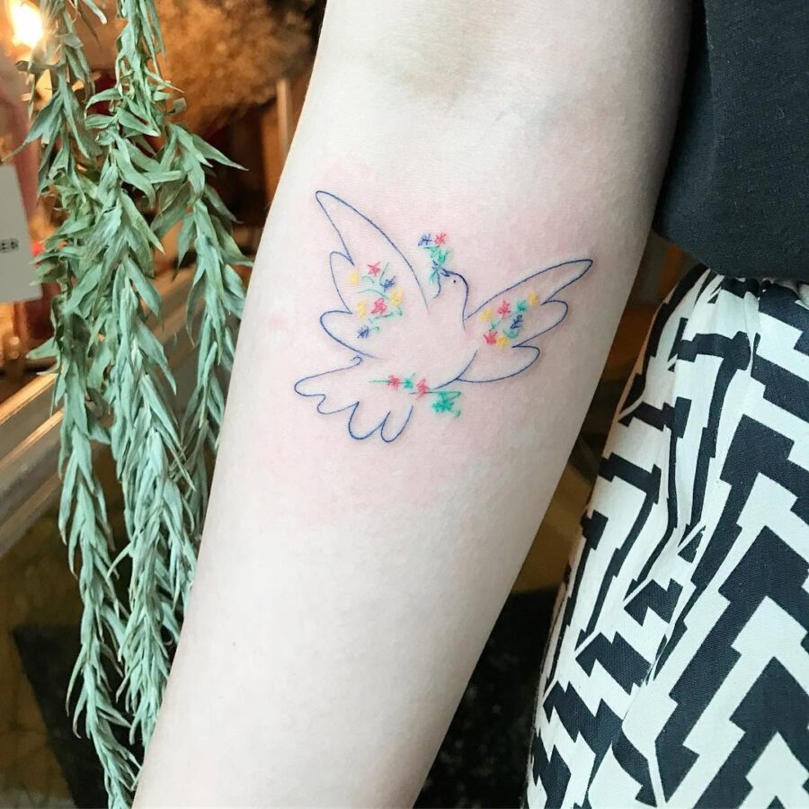 Delicate dove surrounded by colorful flowers Tattoo on skin