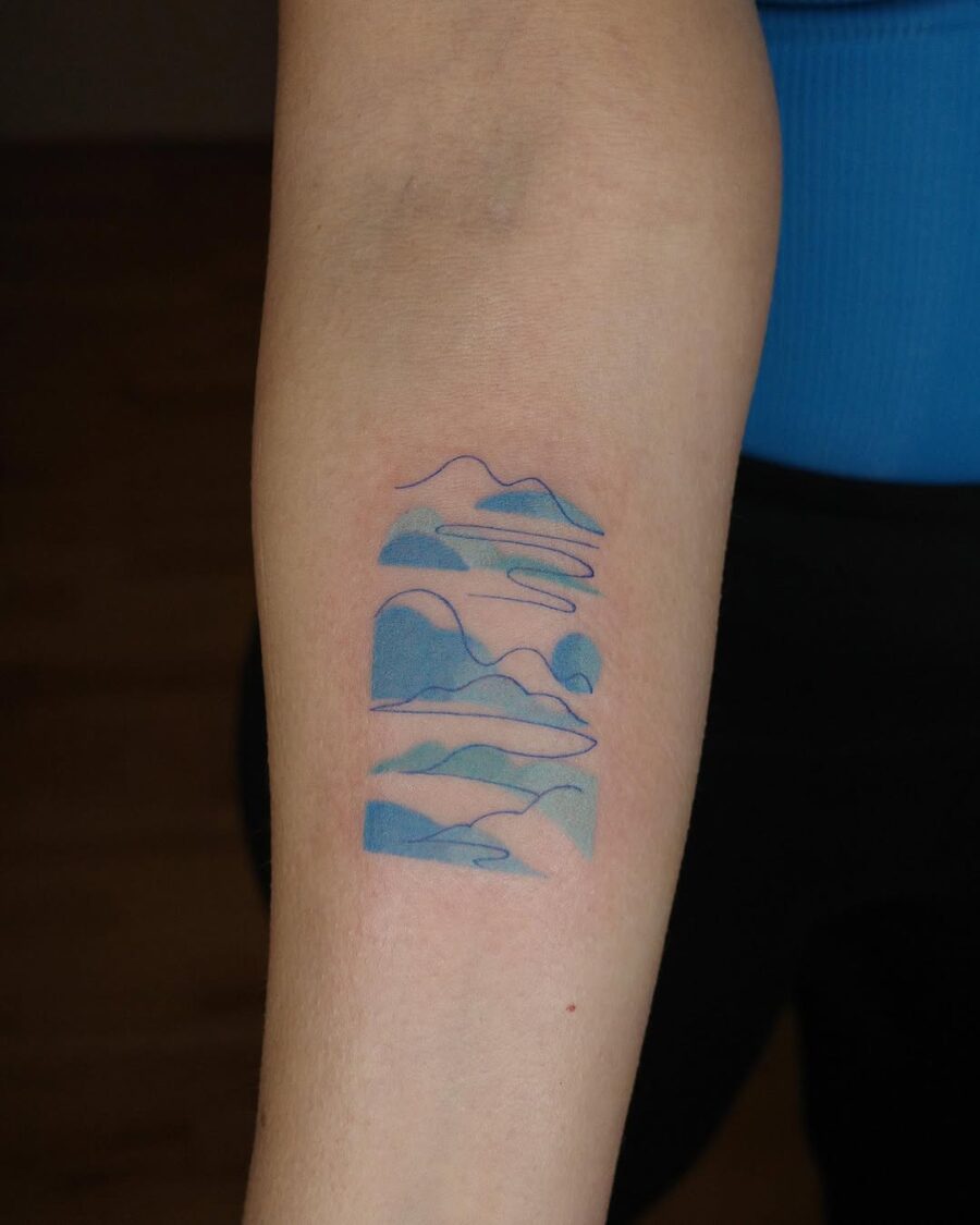 Serene mountains tattoo with calming blue hues Tattoo on skin