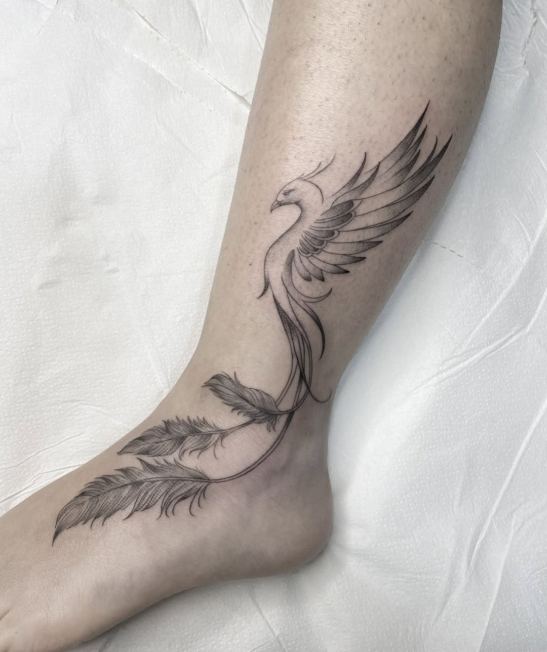 Elegant black phoenix tattoo with feather details. Tattoo on skin
